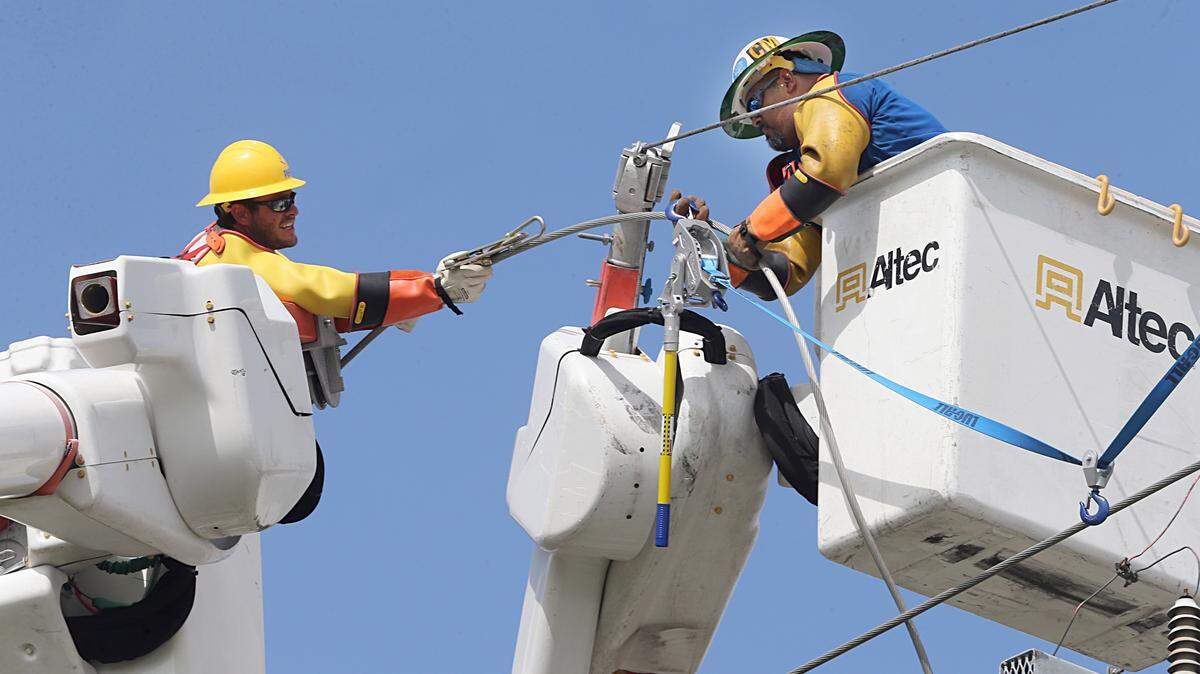 Linemen Titus Beaumonan, left, and Christ Montiel, from the Pike company working with FPL, worked on reconnecting a main power line in Kendall on Sept. 11, 2017.