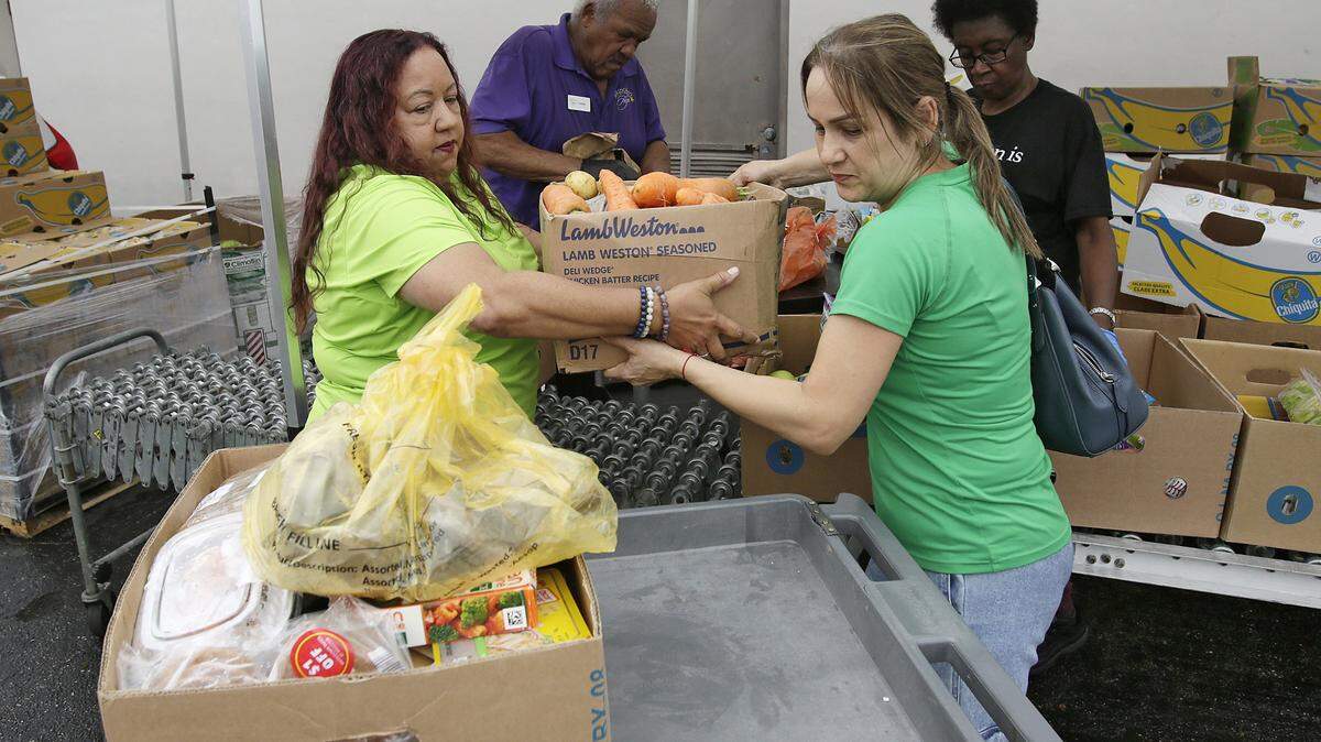 Vanessa Tinsley, co-founder and Executive Director of Bridge to Hope, left, helps Zoe Fernandez of Homestead to place a box of vegetables on a cart that she received from Bridge to Hope on Thursday, September 18, 2025 in Cutler Bay. Andrew Uloza / for Miami Herald