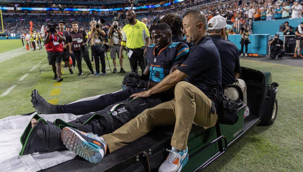 Miami Dolphins wide receiver Tyreek Hill (10) sits next to associate athletic trainer Naohisa Inoue as he is carted off the field after suffering an injury during the second half of an NFL game against the New York Jets at Hard Rock Stadium on Monday, Sept. 29, 2025, in Miami Gardens, Fla.