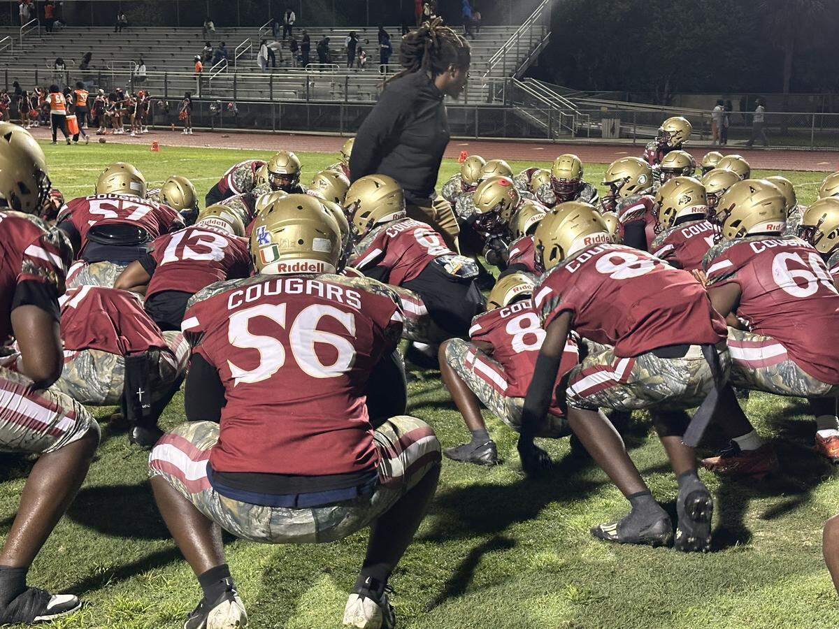 Coconut Creek players huddle around one of their coaches pregame on Friday night before the Cougars beat Piper 33-6 at Coconut Creek High School.
