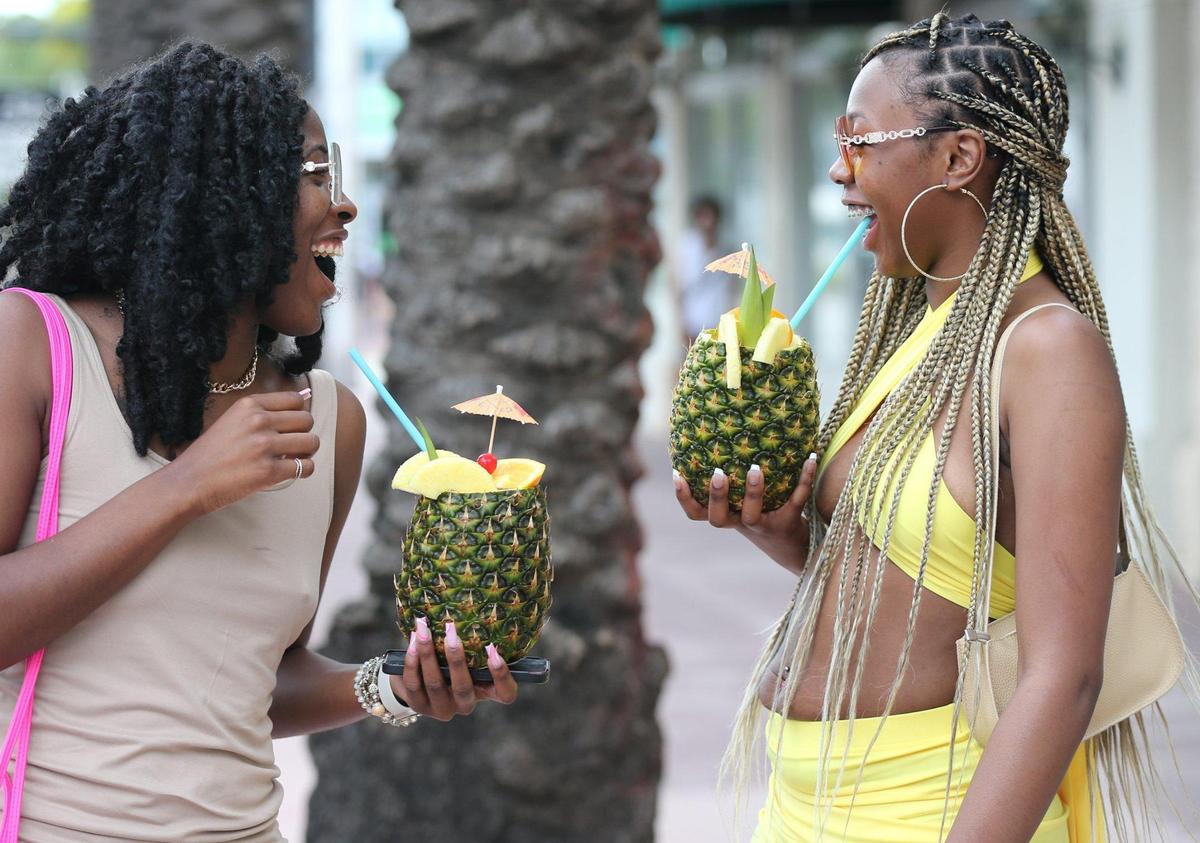 Las hermanas Kanari y Kodi Russell, de izquierda a derecha, de Massachusetts, disfrutan de bebidas tropicales en South Beach, el jueves 17 de marzo de 2022.