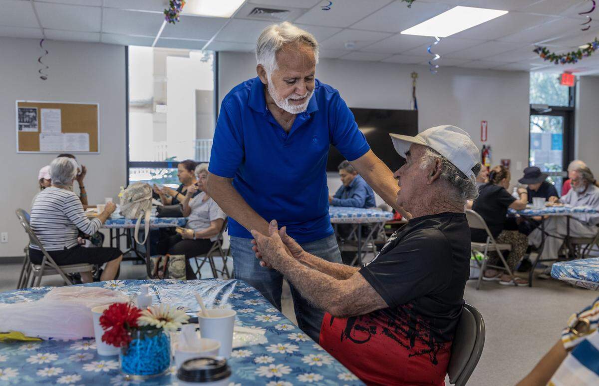 Volunteer and member Raymundo Ricardo (left) greets his friend Rafael Socorro a.ka. “El Gallegito” during lunch time  at the JCS Diener Center in Miami Beach. The center, owned by Jewish Community Services, is one of many programs that stands to lose significant funds due to Miami-Dade County budget cuts.