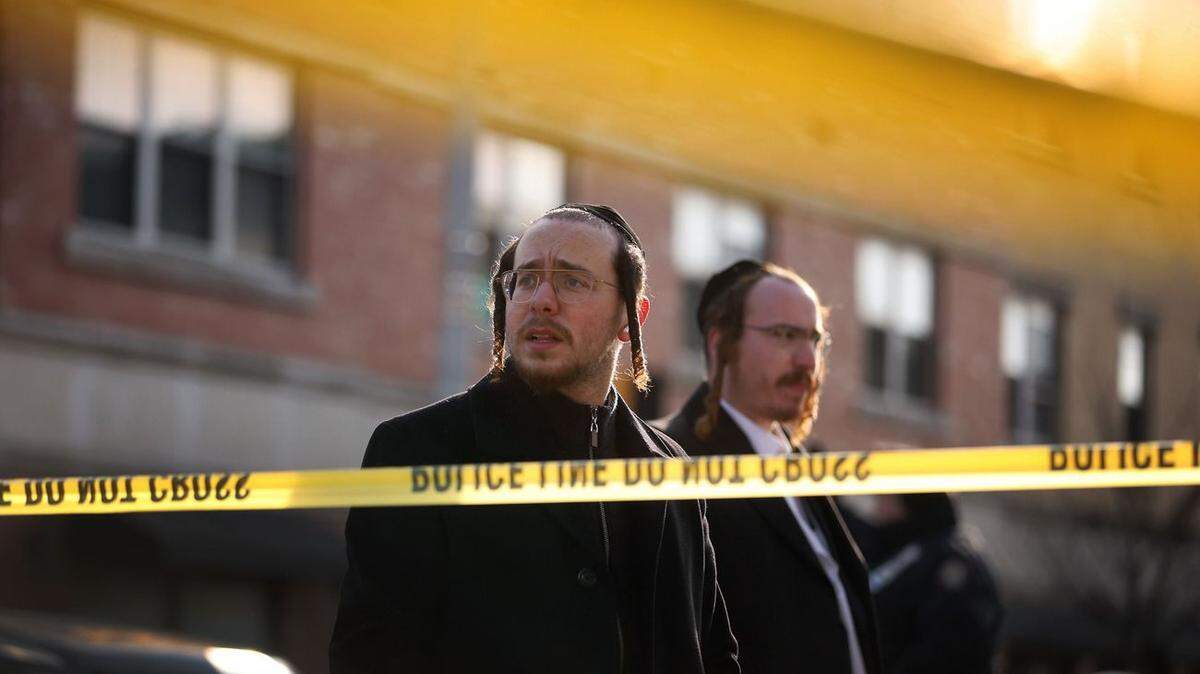 Two men stand at the scene of a shooting at a kosher supermarket in Jersey City. Three people, two of Jewish, were killed. Authorities have labeled the incident a hate crime.