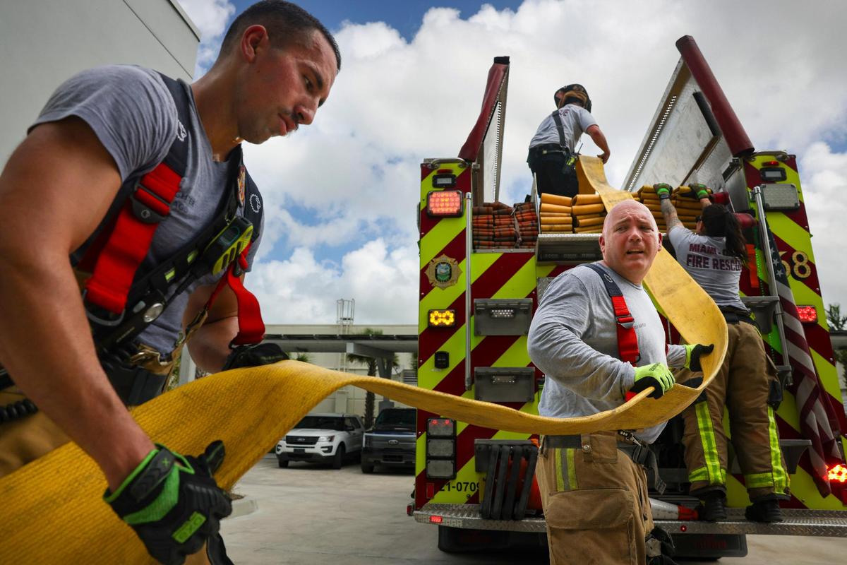 Firefighters Jared Lago, left, and Bibich Zabaleta, right, help put away a fire hose at Dolphin Station 68 in Sweetwater, Florida, on Thursday, April 3, 2025. Also photographed: Lt. Veronica Cordoba in the background and firefighter Chris Carlson in the top of the truck.