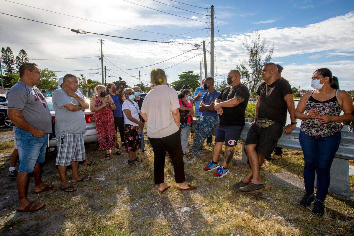 Mobile home park residents who face being evicted from a non-subsidized affordable housing park by developers speak with attorney Davalyn Suarez about the issue near the Miami River in Miami, Florida, on Tuesday, June 1, 2021.