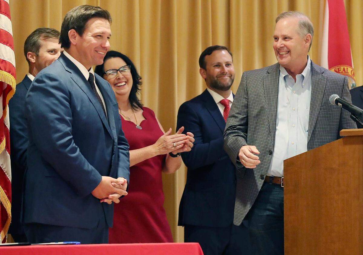 Florida Gov. Ron DeSantis, left, smiles as he is praised by Florida Senate President Wilton Simpson, right, before DeSantis signed a record $109.9 billion state budget Thursday, June, 2, 2022 at The Villages, Fla. DeSantis vetoed many of Simpson’s top priorities, amounting to millions of dollars.