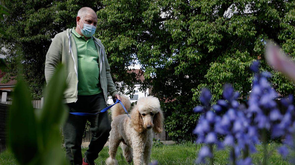 In this stock photo, long COVID patient Gary Miller walks in his garden at home with his dog Rupert in London, Tuesday, May 11, 2021.