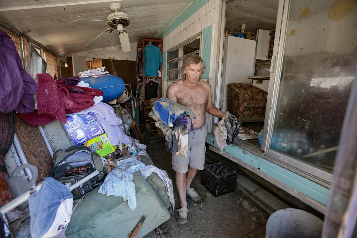 Kim Burke attempts to salvage clothing from his home filled with mud caused by flooding from Hurricane Ian on San Carlos Island on Monday, Oct. 3, 2022.