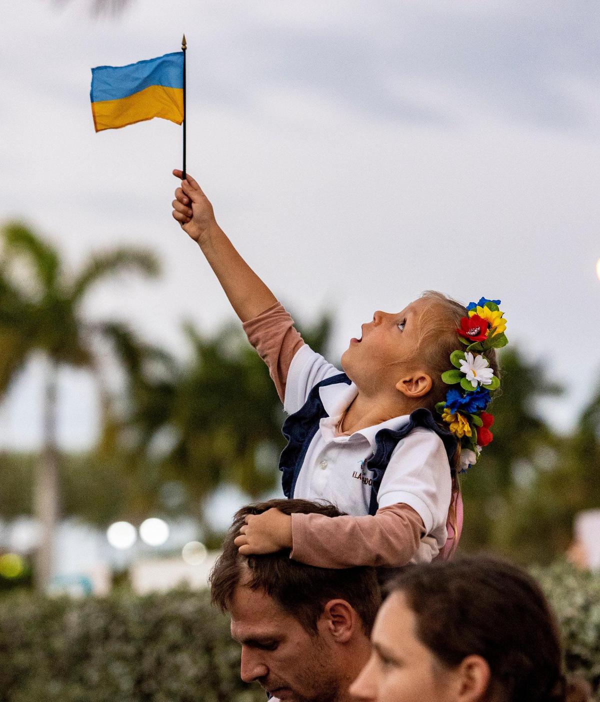 Four-year-old Bruna Biriukova waves a small Ukrainian flag while sitting on her father’s shoulders. Members of the Ukrainian and Russian communities in South Florida gathered in front of Hallandale Beach City Hall in support of Ukraine on Feb. 24, 2022, after Russian forces invaded the country earlier in the day.