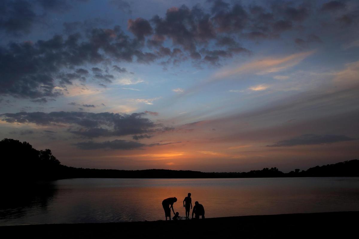A family cools off in Shawnee Mission Lake at dusk Sunday, June 28, 2020, in Lenexa, Kansas. Sunsets and sunrises are more vibrant than usual lately due to dust in the atmosphere from the Saharan dust cloud.