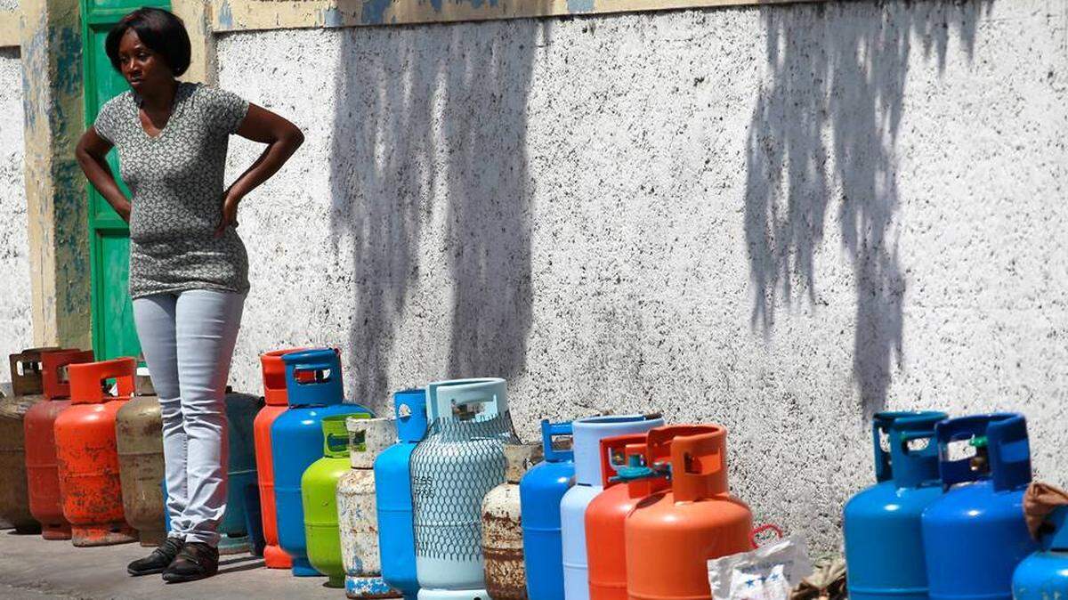 A Haitian woman stands next to empty propane tanks used to mark their owners’ places in a line for fuel.