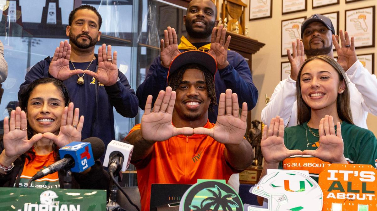 St. Thomas Aquinas running back Jordan Lyle holds up the ‘U’ with his hands while surrounded by family and coaches during signing day at St.Thomas Aquinas High School in Fort Lauderdale, Florida, on Wednesday, December 20, 2023. Lyle will attend the University of Miami