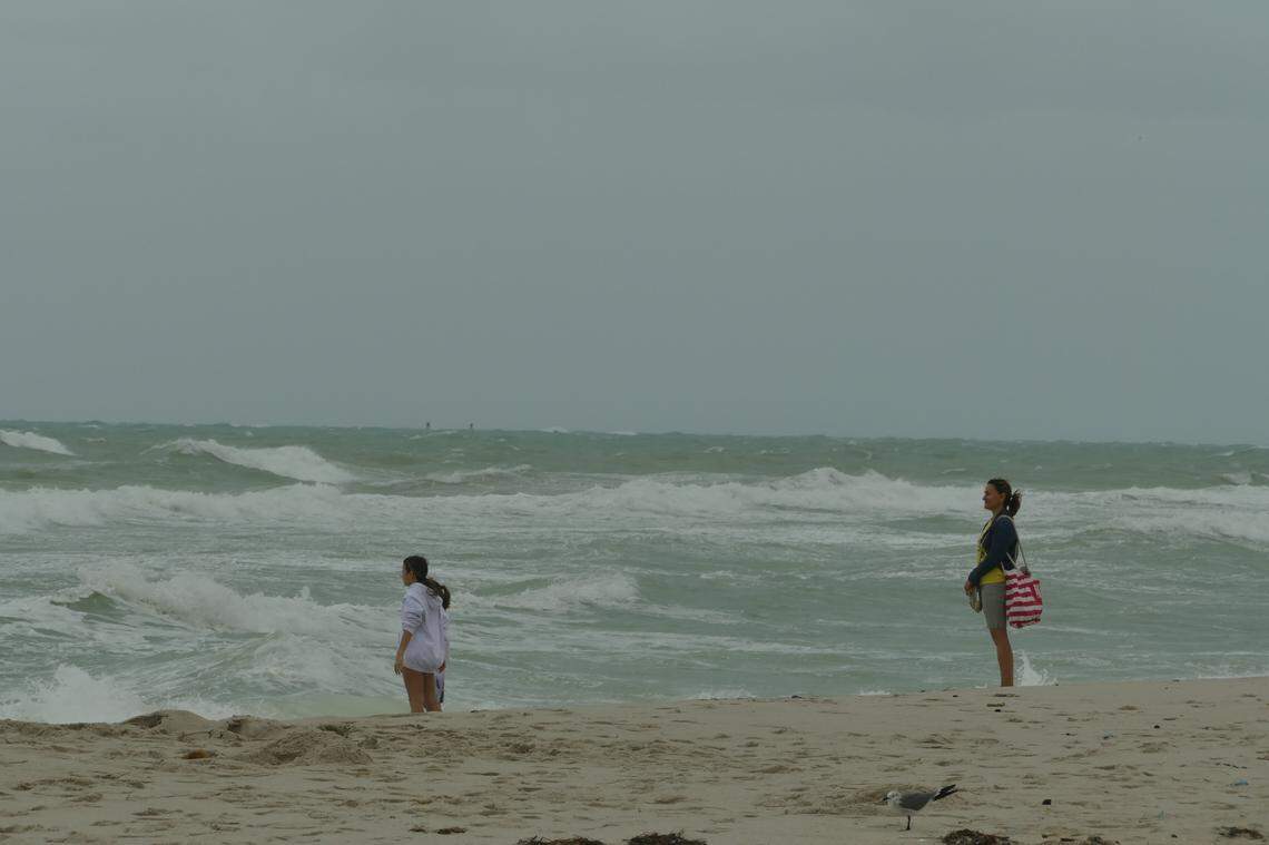 A woman observes two girls as they dip their feet in the water in Miami Beach, Florida, on Friday, Dec. 15, 2023.