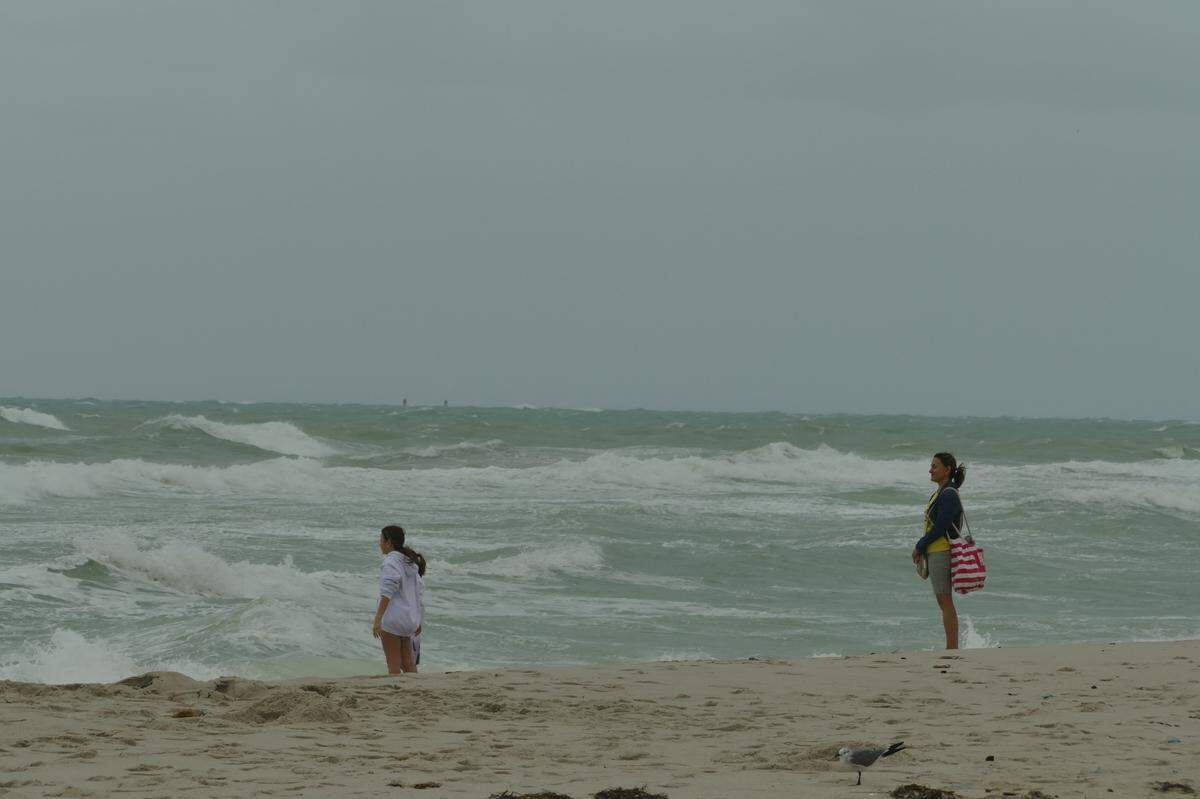 A woman observes two girls as they dip their feet in the water in Miami Beach, Florida, on Friday, Dec. 15, 2023.