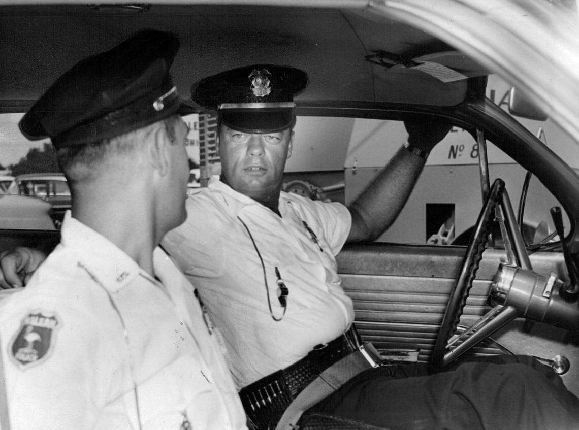 In 1961, Hialeah Police Officer William Connell, right, and John Herman demonstrate the safety belts recently installed in all patrol cars. Hialeah was the first city in Miami-Dade County to utilize the belts.. Initial reaction among the police officers has been enthusiastic.