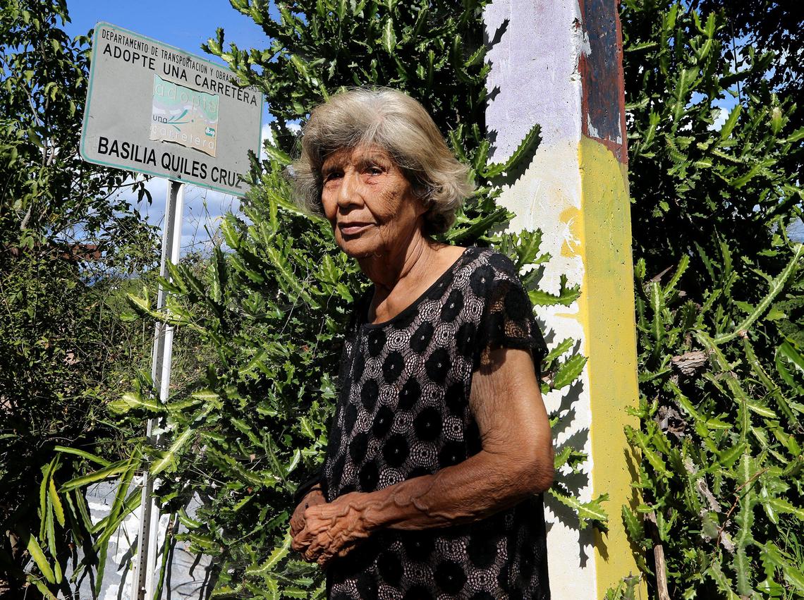 Basilia Quiles Cruz, 79, stands next to a street sign bearing her name. She decided to stay in her family home where she grew up in Guánica in southern Puerto Rico, although many houses nearby have been damaged by several earthquakes.