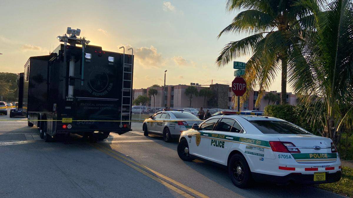 Miami-Dade police at the entrance to an apartment complex where two people died in shootings.