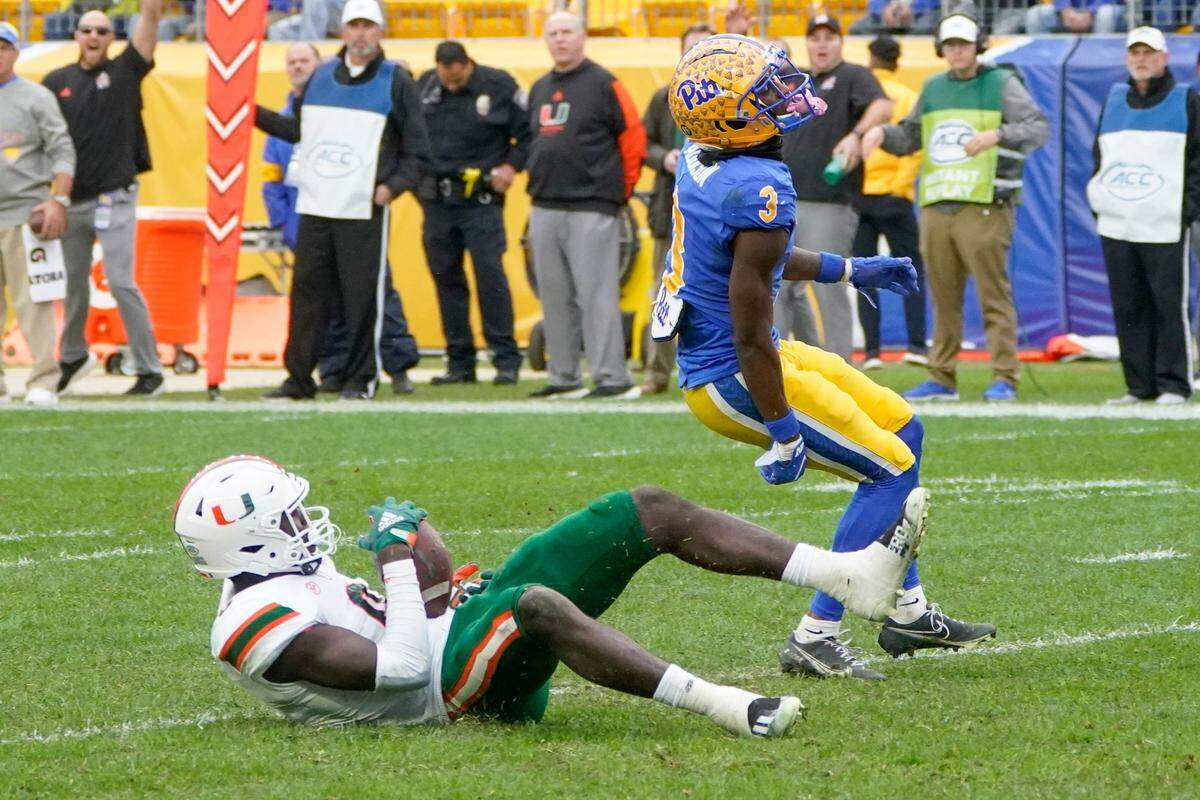 Miami safety James Williams (0) rolls over after making an interception intended for Pittsburgh wide receiver Jordan Addison (3) during the second half of an NCAA college football game, Saturday, Oct. 30, 2021, in Pittsburgh. The play was reviewed and confirmed an interception. Miami won 38-34. (AP Photo/Keith Srakocic)