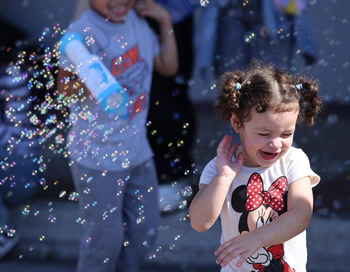 Acenet Antonella, 2, right, runs playfully as Dylan Taylor Vega, 4, blows bubbles with a “bubble gun.”  