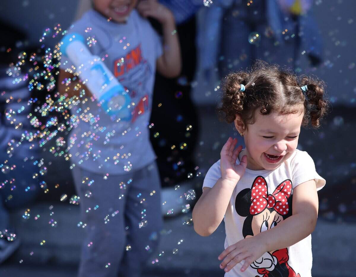 Acenet Antonella, 2, right, runs playfully as Dylan Taylor Vega, 4, blows bubbles with a “bubble gun.”