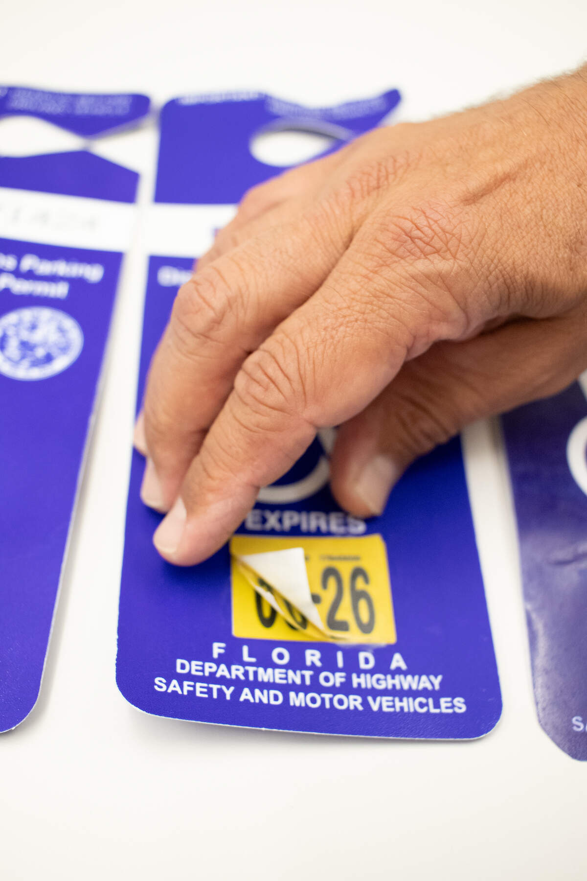 A Coral Gables parking enforcement officer on April 30, 2026, shows an example of one of the fraudulent disability parking permits that has been confiscated in the city. This was an expired permit with fake stickers that were meant to make it look like it was still active.
