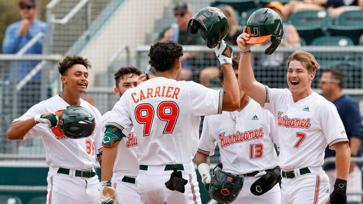 Miami Hurricanes right fielder Lorenzo Carrier (99) is congratulated by teammates after hitting a grand slam during the second inning of an NCAA baseball game against the Towson Tigers in Alex Rodriguez Park at Mark Light Field on Sunday, February 20, 2022 in Coral Gables.
