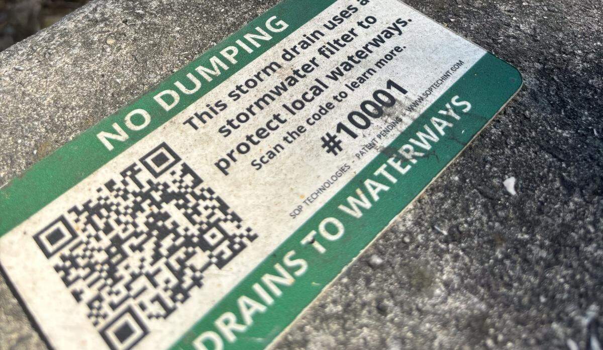 A placard located at NW 15th Ct and NW 95th St for one of the pilot installation projects instructs Miami residents to report damage or overflowing pollution in drains.