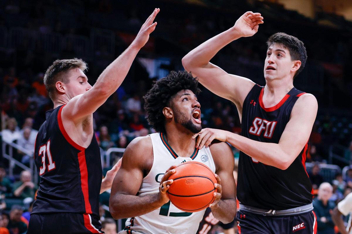 Miami Hurricanes forward Norchad Omier (15) protects the basketball from St. Francis Red Flash guard Brad McCabe (31) and forward Josh Cohen (33) during the second half of a basketball game at the Watsco Center in Coral Gables, Florida, on Saturday, December 17, 2022.