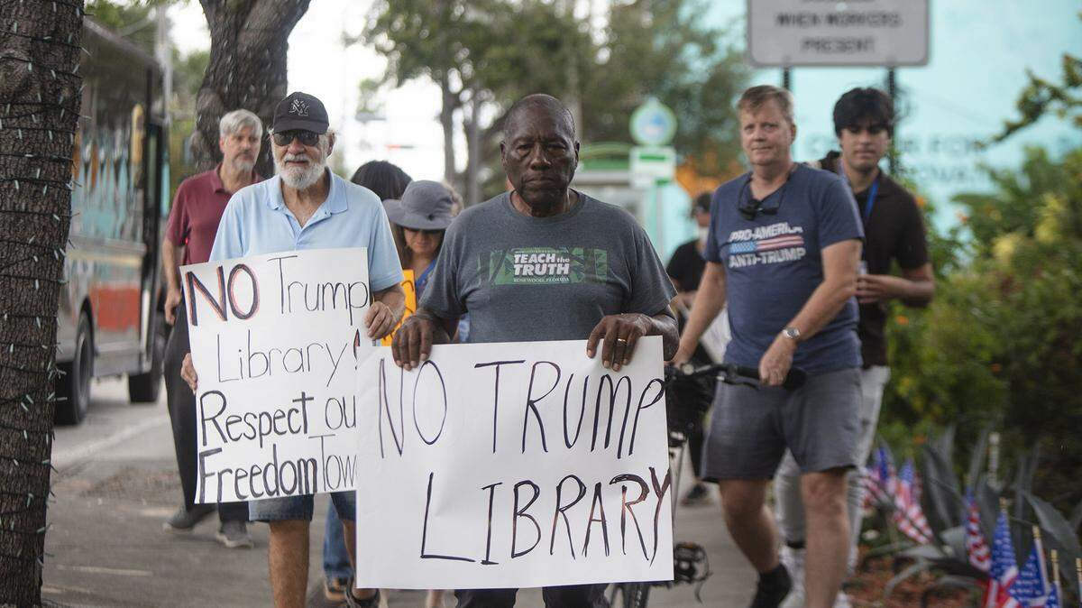 Activist and historian Marvin Dunn walk with protesters about Miami's history outside the Kaseya Center, where former President Donald Trump made an appearance. Demonstrators carried signs and chanted against his policies and a proposed land transfer for Trump's presidential library. The protest took place in Miami on Wednesday, Nov. 5, 2025.