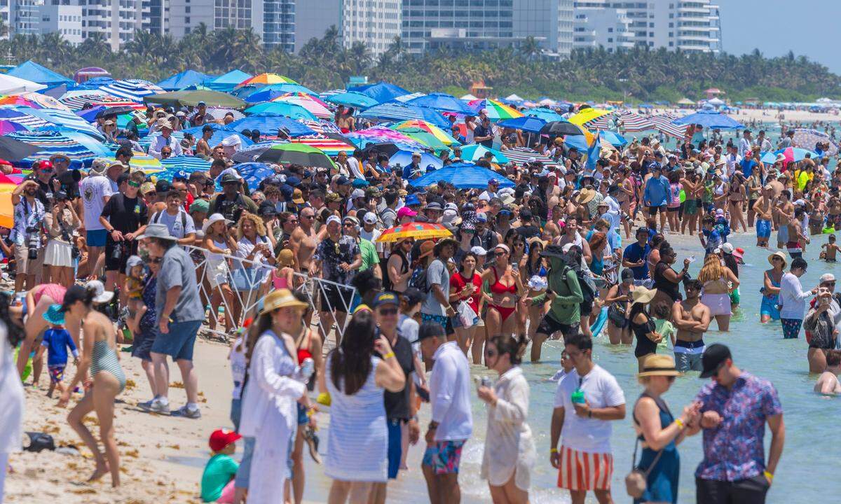 Beachgoers look skyward as several Army aircraft, including a USAF Northrop B-2 Spirit (center), fly over South Beach during the Hyundai Air & Sea Show—part of Miami Beach’s annual National Salute to America’s Heroes—on Saturday, May 24, 2025.