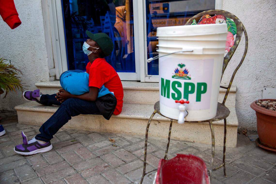 A boy who was deported from the United States sits on the ground after arriving at a hotel where he will be quarantined as a measure against the spread of the new coronavirus, in Tabarre, Haiti, Thursday, April 23, 2020.