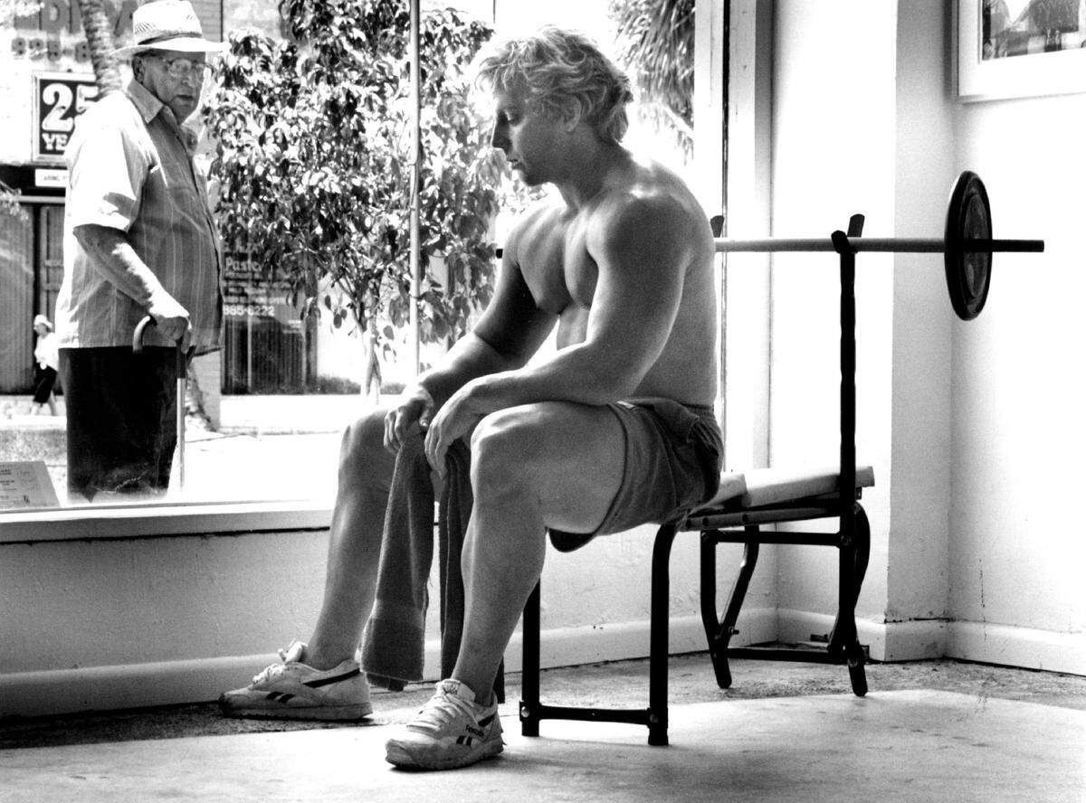 A Miami Beach resident looks at the “Weight Lifter” sculpture created by Duane Hanson on display on Lincoln Road in 1994