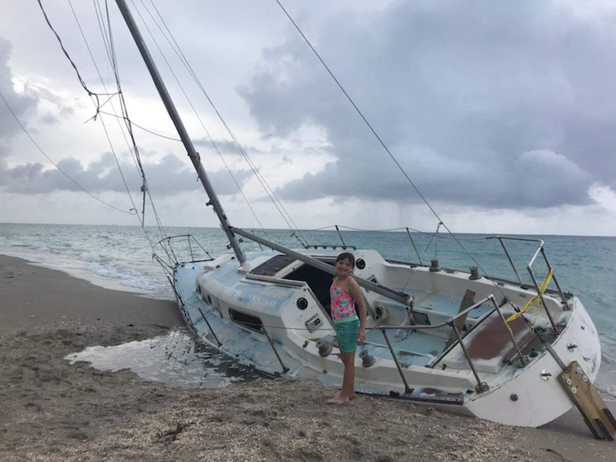 Morgan Baur, 8, poses in front of the abandoned boat. Children climb the deck and a lifeguard routinely blows his whistle.