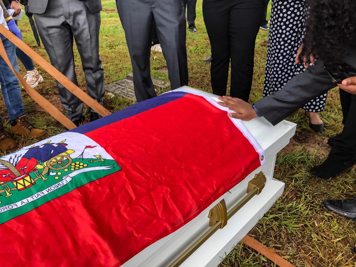 Una mujer coloca su mano en el ataúd de una de las 11 mujeres haitianas que murieron el mes pasado cuando el barco sobrecargado en el que viajaban volcó, en San Juan, Puerto Rico, el miércoles 15 de junio de 2022.
