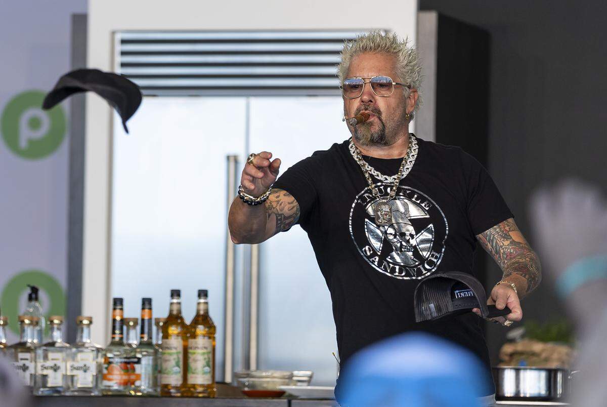 American celebrity chef Guy Fieri throws hats from a stage toward guests attending the Goya Foods' Grand Tasting Village during the Food Network South Beach Wine & Food Festival on Saturday, Feb. 21, 2026, in Miami Beach, Fla.