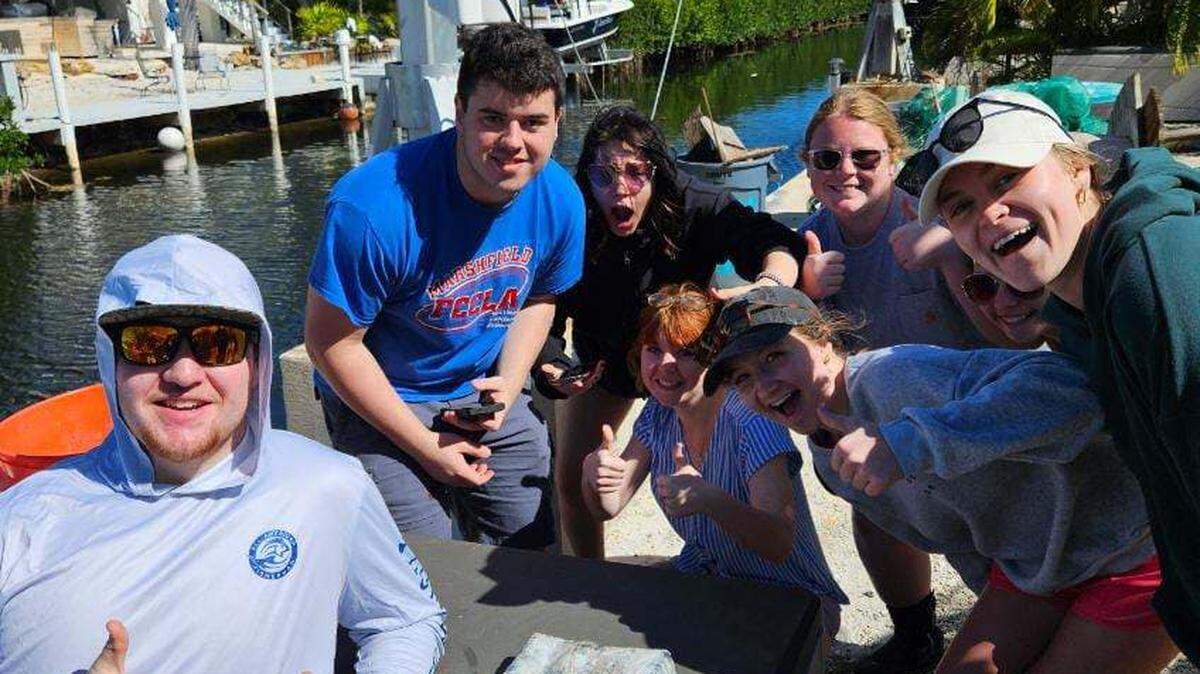 A group of high school students from Missouri gathers around a 2.5-pound brick of cocaine Monday, Jan. 29, 2024, they found while volunteering with the Conch Republic Marine Army, a conservation group that cleans trash on the water and shoreline in the Florida Keys.