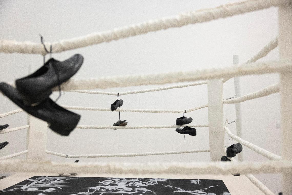 Tap shoes slung over the sides of a boxing ring depict the line between entertainment and sport in Gary Simmons "Public Enemy" exhibit. According to the description, “the works in this room imply absent bodies, prompting visitors to conjure their own mental images who might populate these settings. By removing these figures from these scenes, Simmons suggests that, as Black bodies are sensationalized and marketed, the individuality of Black subjects is erased and replaced by racial stereotypes.”