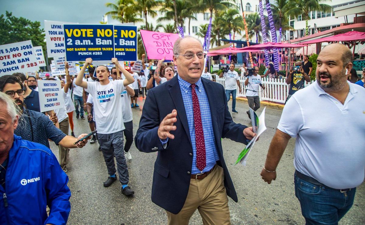 Gelber is followed to his car by protesters chanting and waving signs in opposition to a proposed 2 a.m. cutoff on alcohol sales on Ocean Drive in South Beach on Oct. 22, 2021.