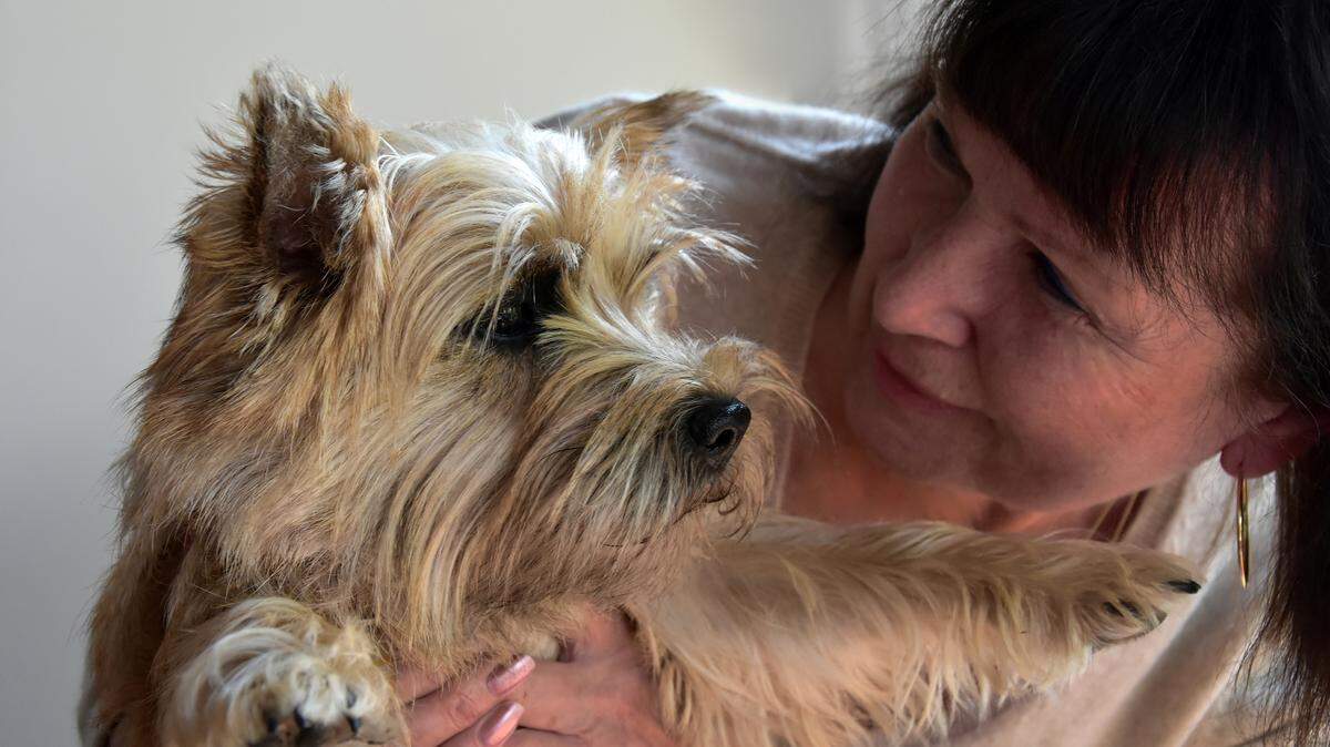 An older woman cuddles with her puppy.