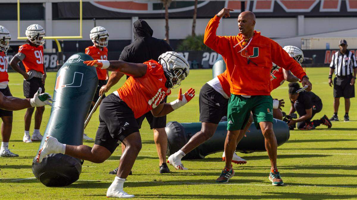 Miami Hurricanes defensive lineman Simeon Barrow Jr. (10) runs through blocking drills as defensive lineman coach Jason Taylor directs him during practice drills at the Carol Soffer Indoor Practice Facility on Thursday, August 1, 2024, in Coral Gables, Fla.