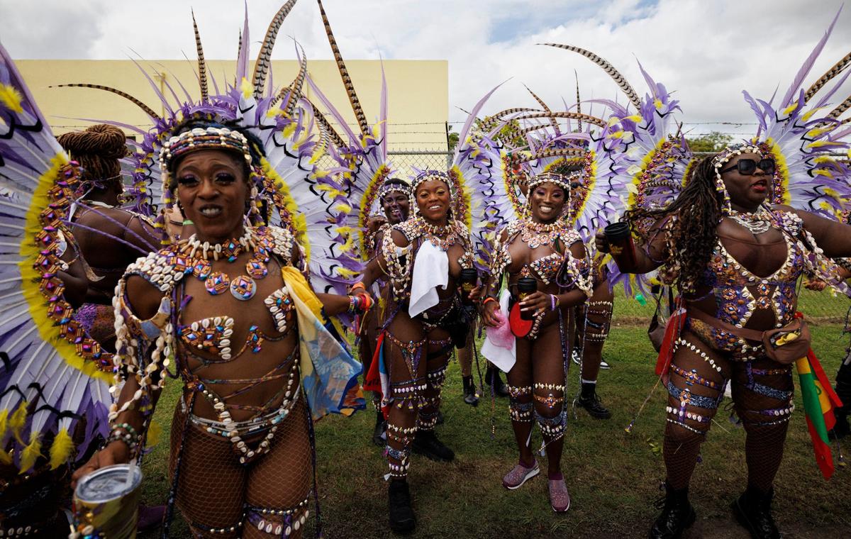 Zarinah Inyangm, center left, and Paula Maynard, center right, smile while dancing with out masqueraders in the “Party Room Squad” band before the Parade of Bands at Miami Carnival on Sunday, Oct. 13, 2024, at Miami-Dade County Fair Expo. This year was Inyangm’s first Carnival.