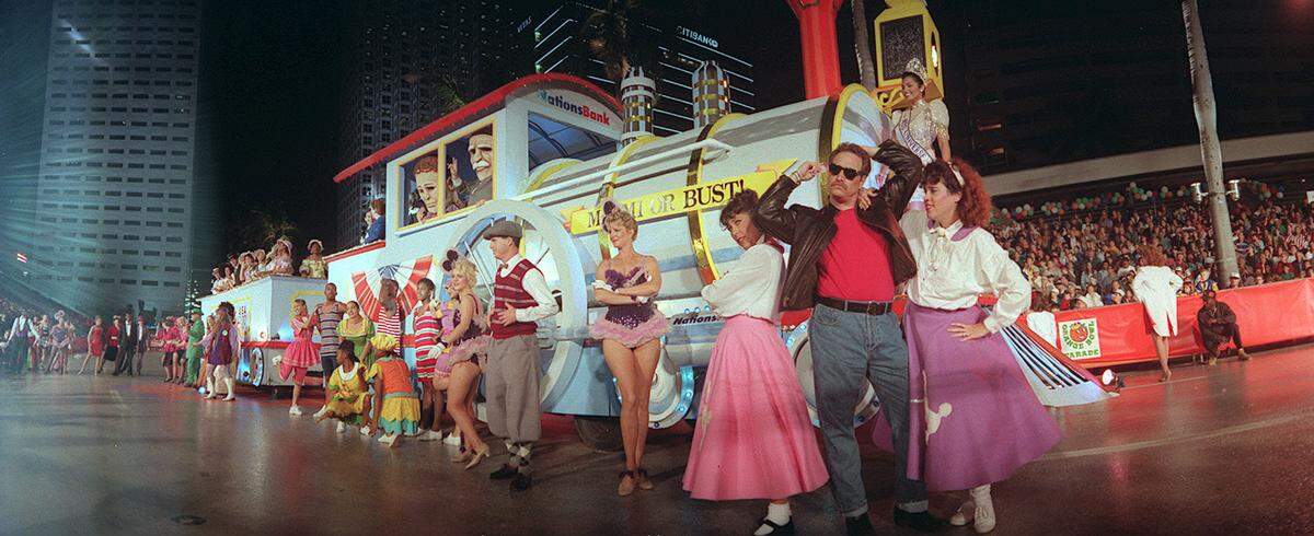In this file photo, entertainers perform in front of a bank float in downtown Miami.