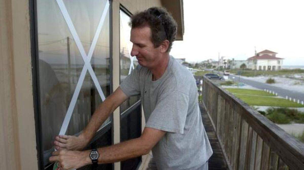 A Pensacola Beach resident tapes windows in advance of Hurricane Ivan in 2004. Florida PACE program gives homeowners money to better secure their homes, installing storm-impact windows, for example. 
