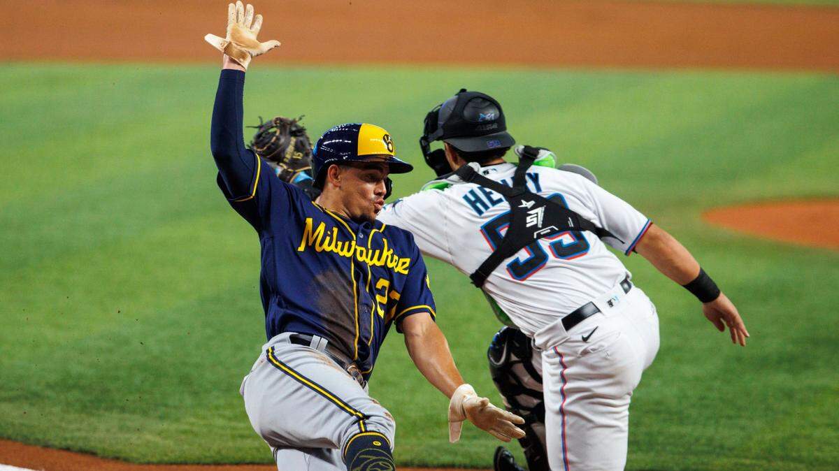 Milwaukee Brewers shortstop Willy Adames (27) scores as Miami Marlins catcher Payton Henry (59) unable to apply a tag during the first inning of a baseball game at LoanDepot Park on Sunday, May 15, 2022 in Miami, Florida.
