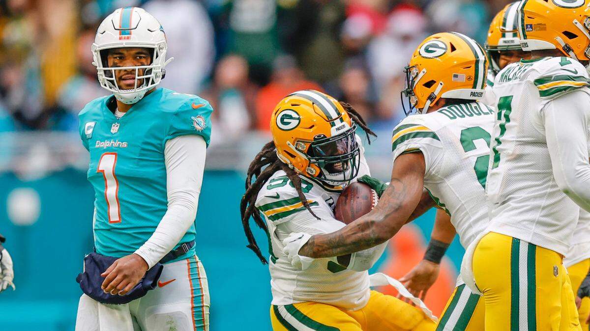 Miami Dolphins quarterback Tua Tagovailoa (1) walks off the field as Green Bay Packers linebacker De’Vondre Campbell (59) celebrates with teammates after an interception in the fourth quarter Hard Rock Stadium in Miami Gardens, Florida on Sunday, December 25, 2022.