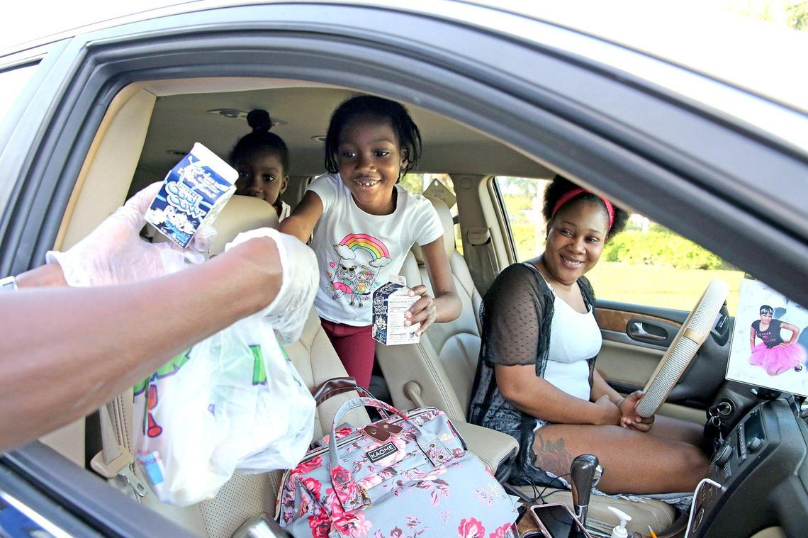 A family gets three breakfasts at Dillard High School in Fort Lauderdale, Florida, March 16, 2020. Broward County schools are closed because of COVID-19 concerns, and the school is providing breakfast and lunch via drive-by service.