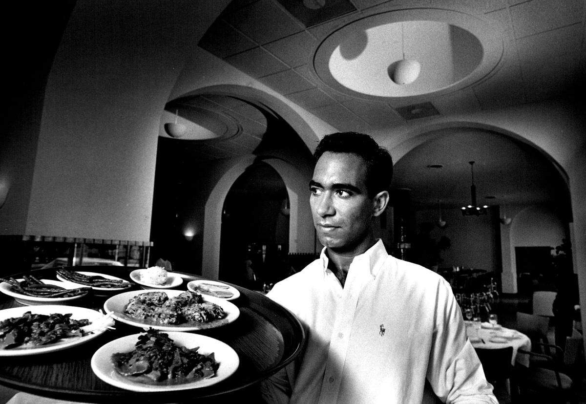 Waiter Juan Jose carries a tray of food through the archways of The Strand at 671 Washington Ave.