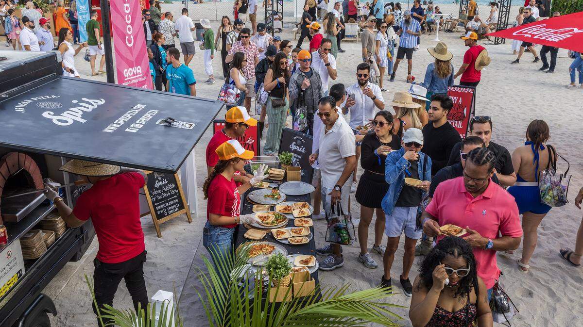 Guests line up to try pizza at a booth at the Grand Tasting Village at the 2025 South Beach Wine & Food Festival. This year the Grand Tasting Venue will host an evening event, a concert by music producer and DJ Diplo, on opening night that will feature bottle service and VIP packages.