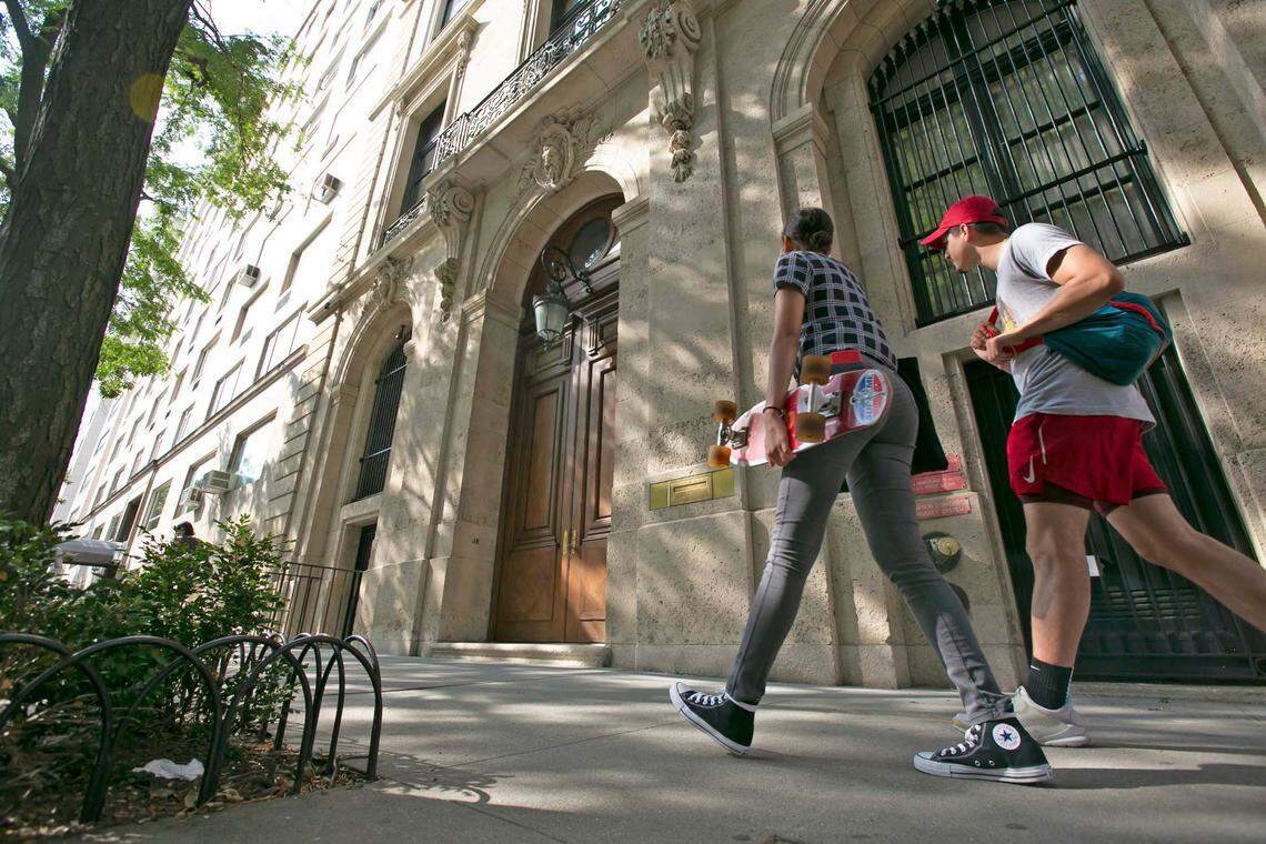 People walk by the Upper East Side New York estate of deceased mulitmillionaire Jeffrey Epstein. Damage on the front doors of Epstein’s residence was caused by agents serving a search warrant following Epstein’s arrest at a nearby New Jersey airport Saturday July 6, 2019 .