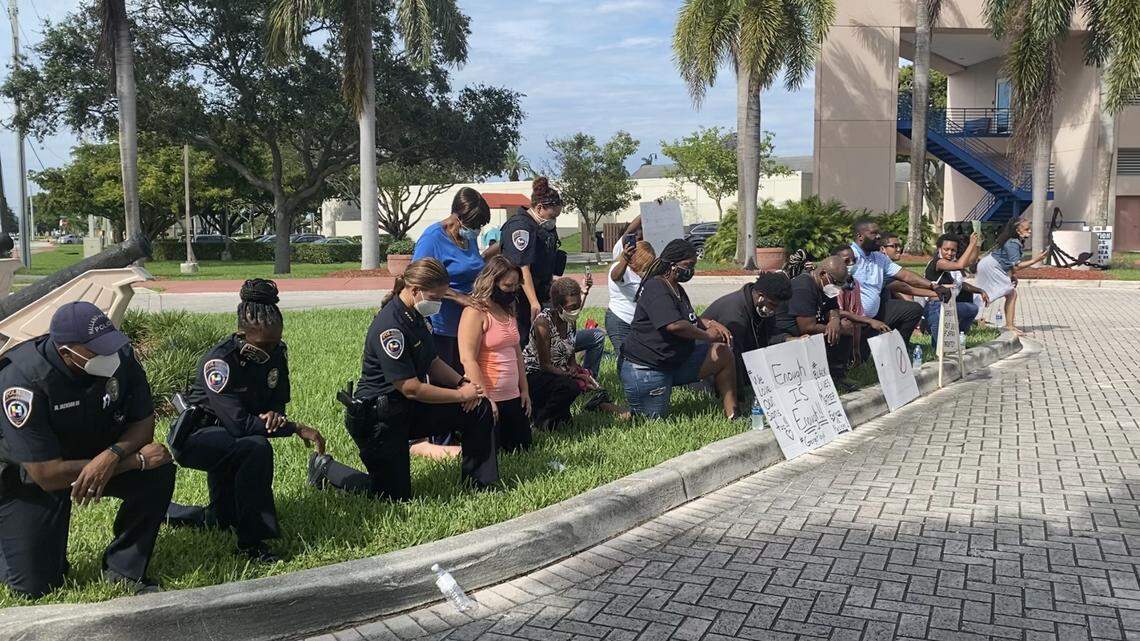 Hallandale Beach Police Chief Sonia Quinones and other officers kneeling with protesters.
